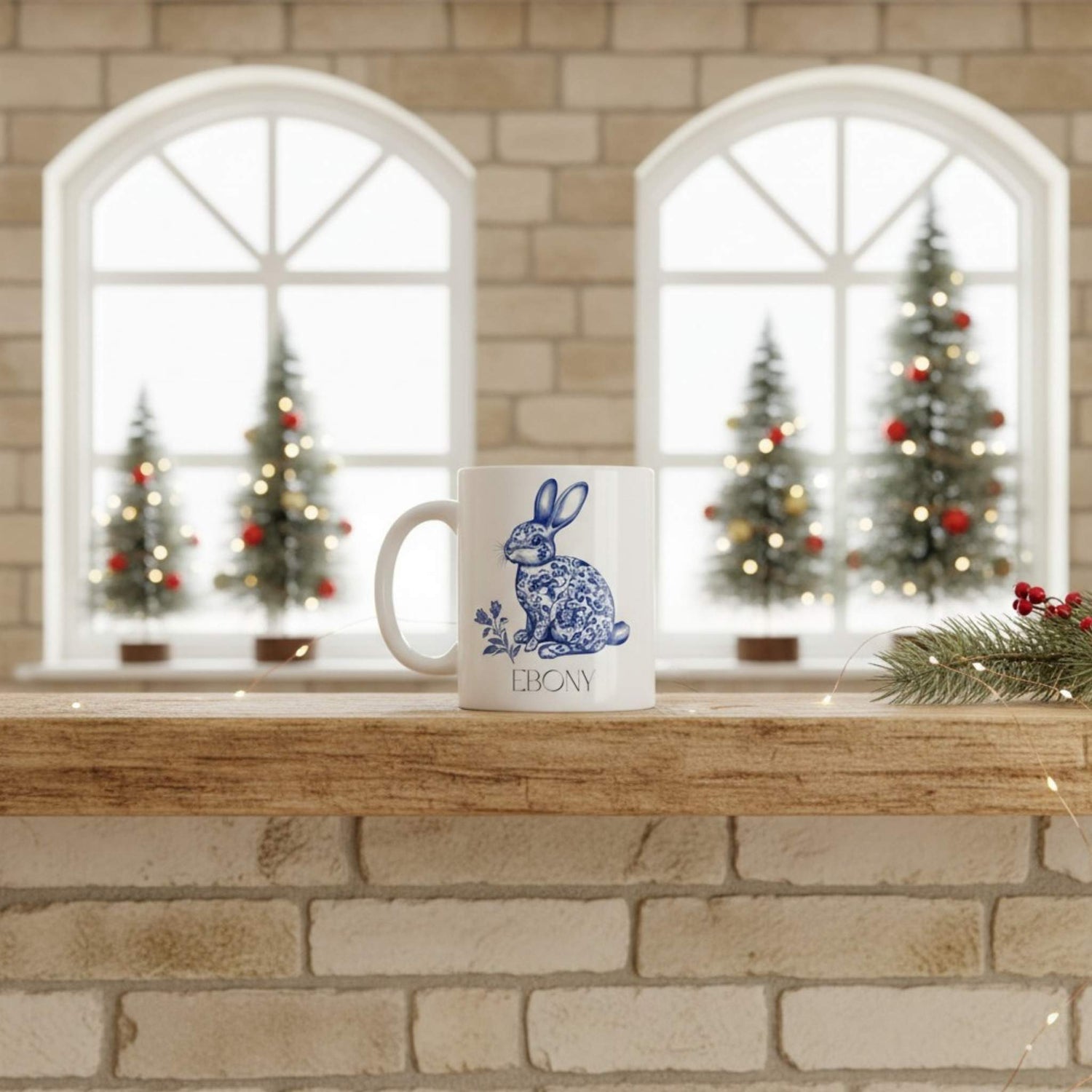 White mug with blue hare design on a wooden surface with Christmas trees in the background.