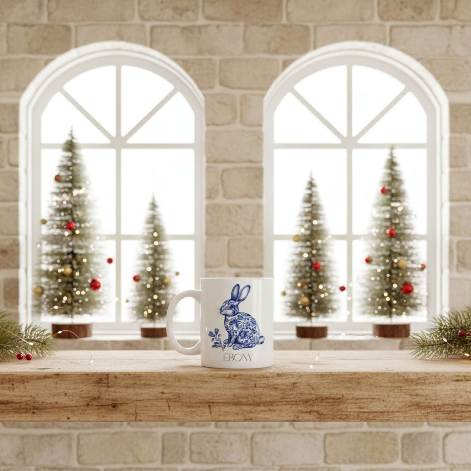 White mug with blue hare design on a windowsill with Christmas trees in the background.