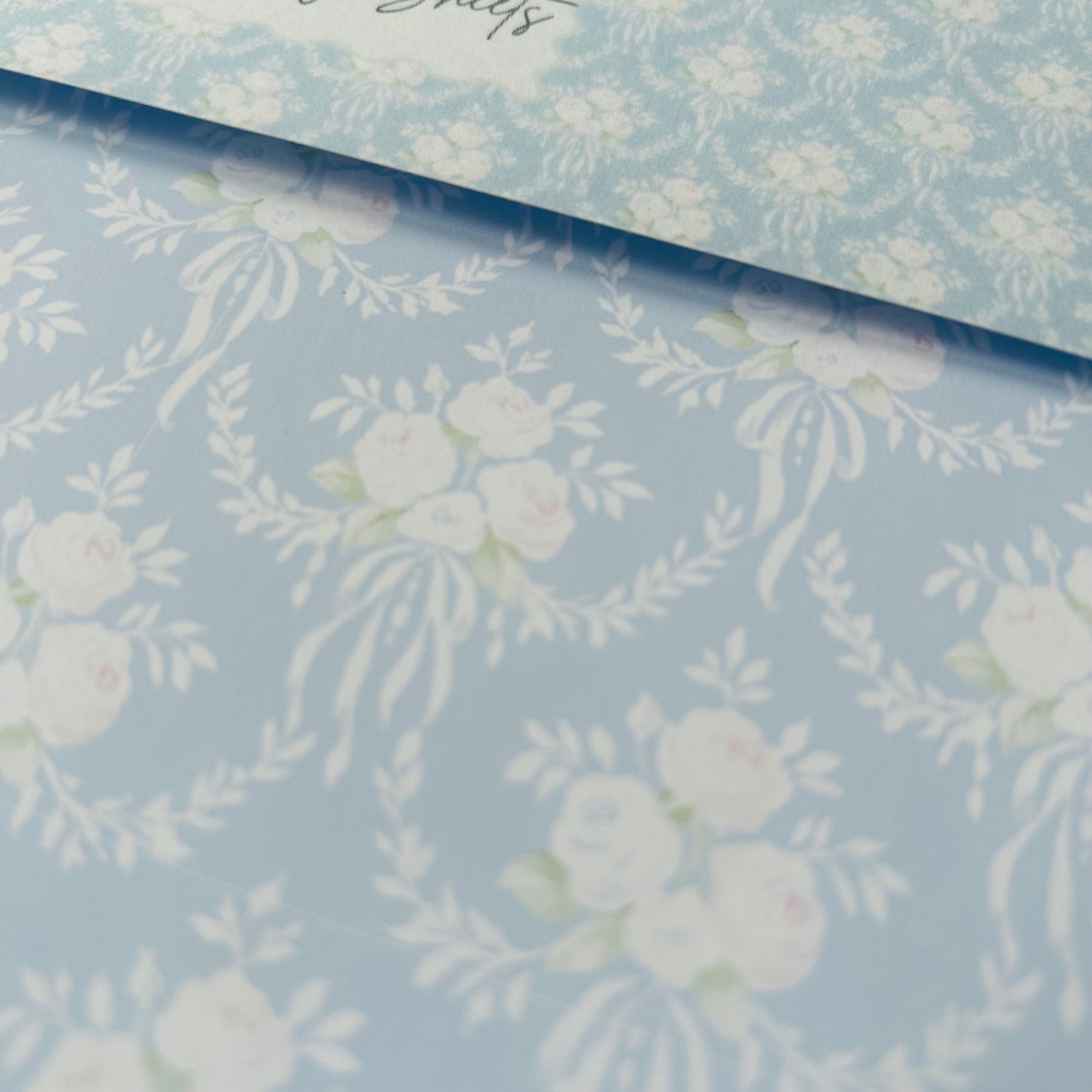 Floral patterned paper with white flowers on a light blue background
