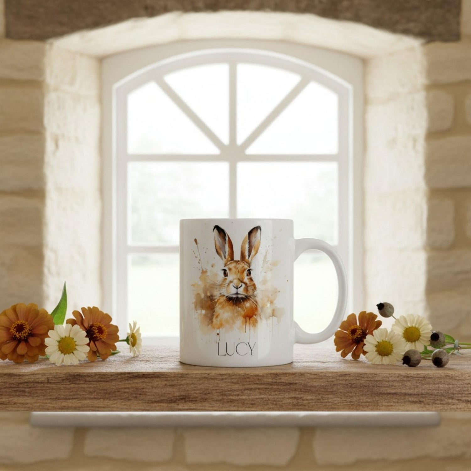 Mug with a hare design and 'LUCY' text on a windowsill with flowers.