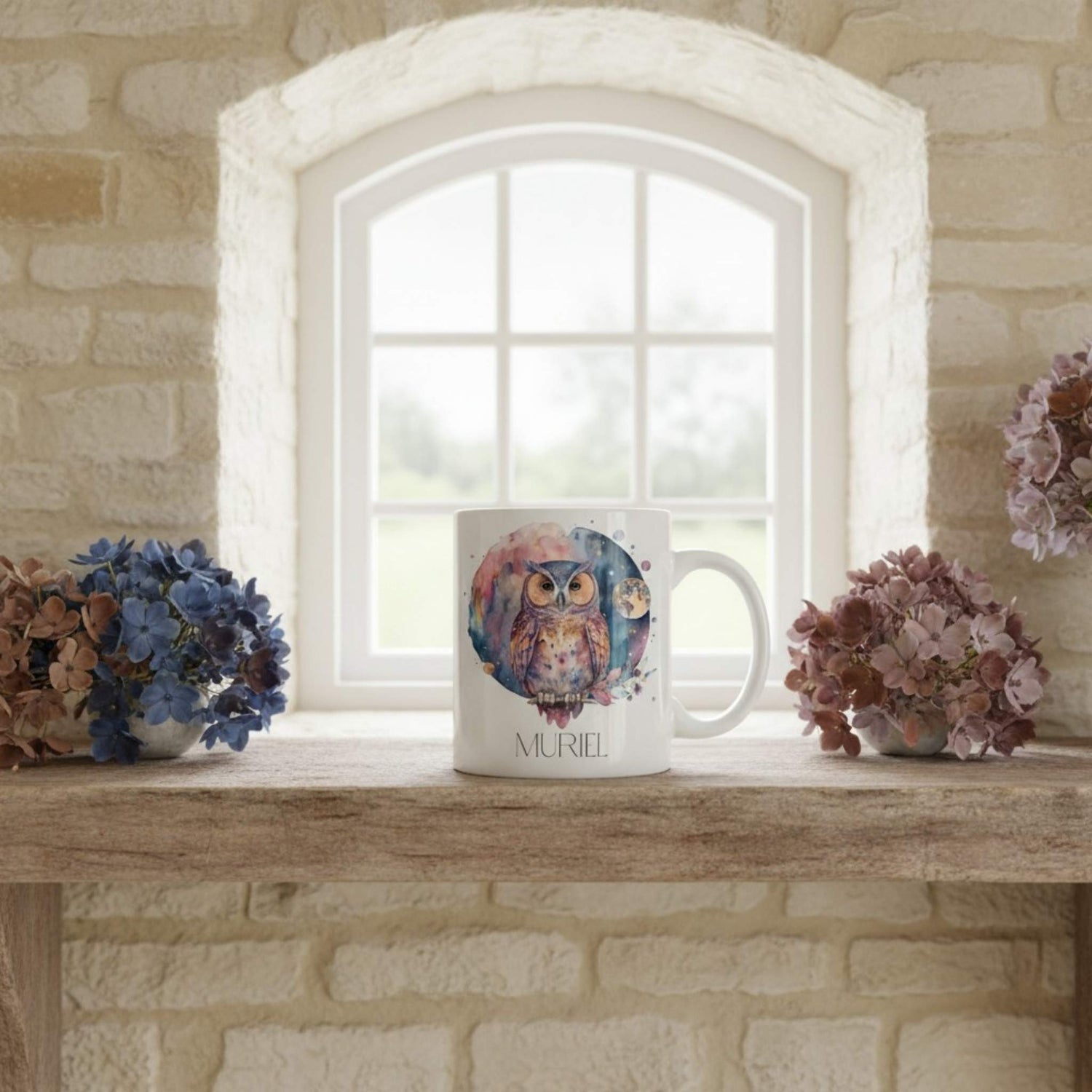 White mug with owl design on a wooden surface in front of a window.