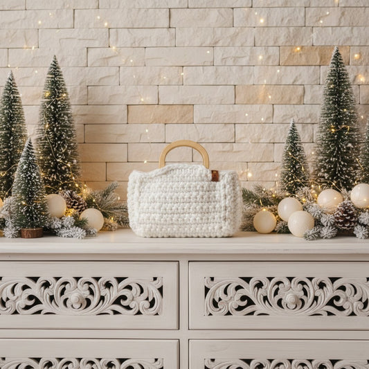White textured handbag on a decorative surface with Christmas trees and lights in the background.