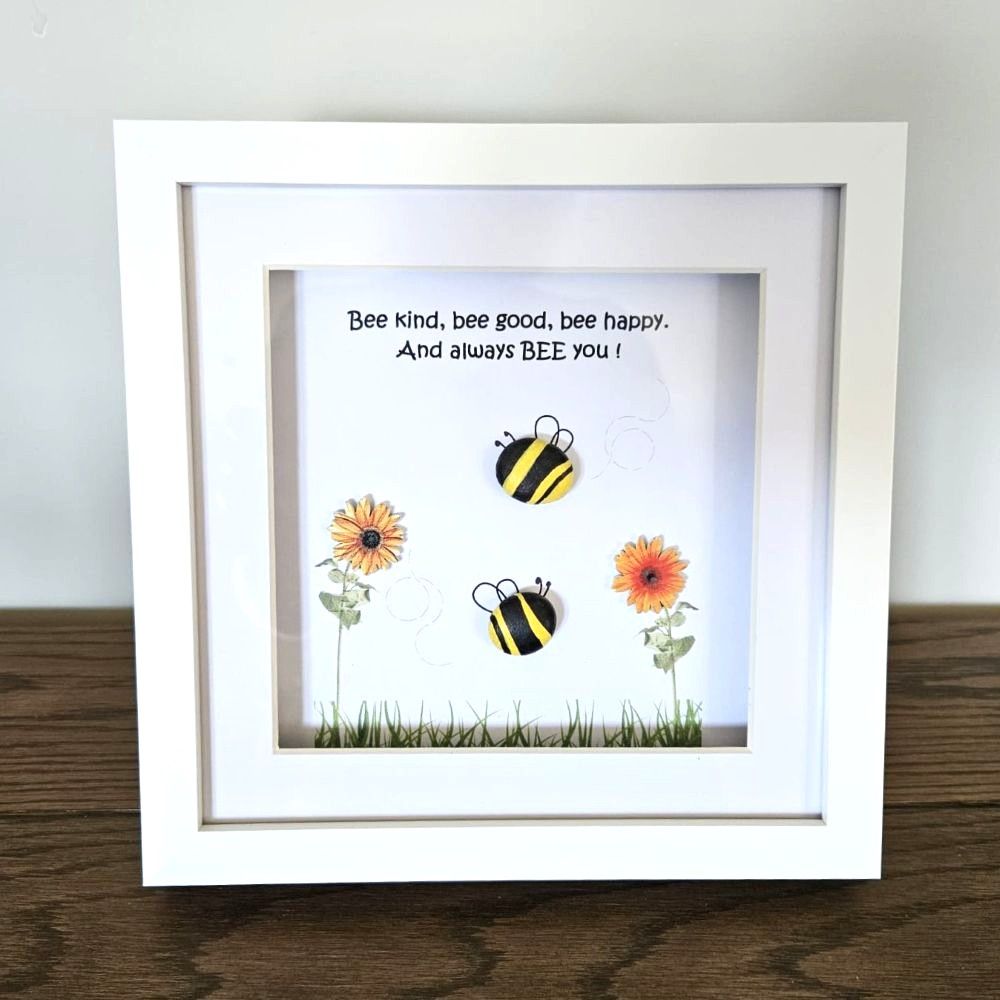 Framed artwork with bees and flowers on a wooden surface