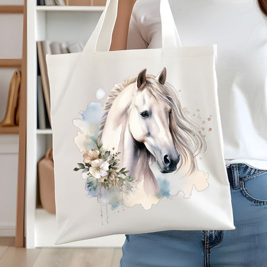 White tote bag showing a white horse head with long flowing mane. Pale coloured flowers decorate. The bag is being held up by a woman in denim.
