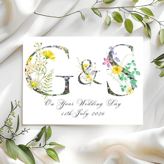 Wedding card with floral monogram and date on a white fabric background