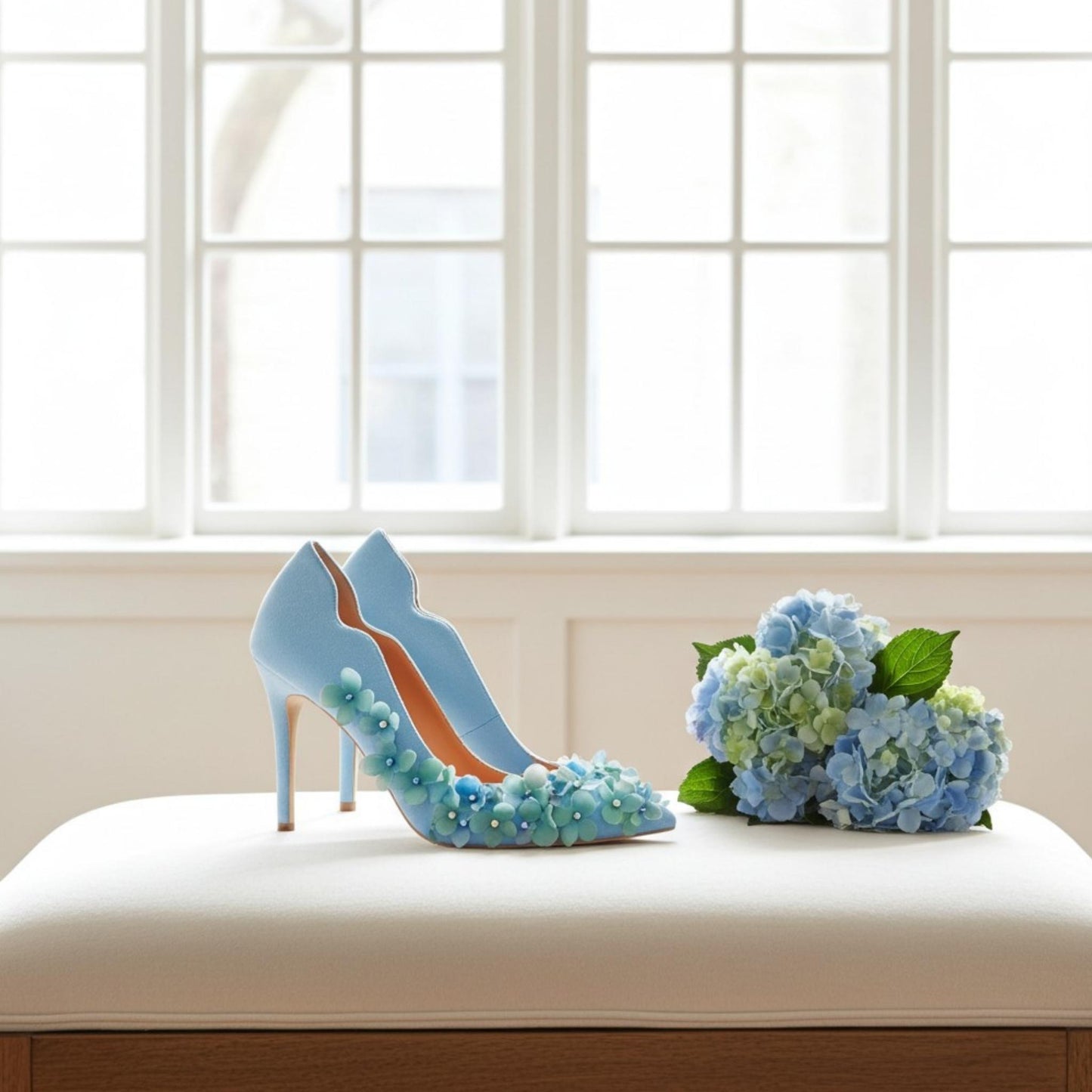 Blue high-heeled shoes with floral details next to a bouquet of blue flowers on a white surface.