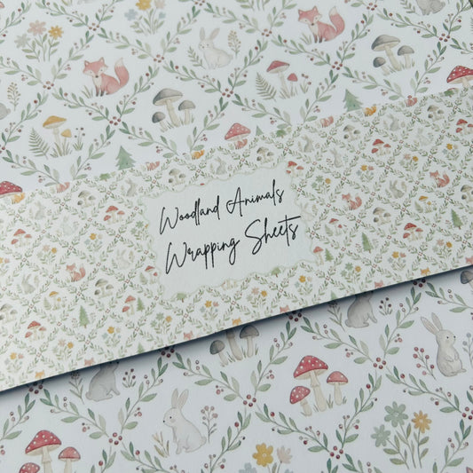 Woodland animals wrapping sheets with fox, rabbit, and mushroom design on a light off white background.