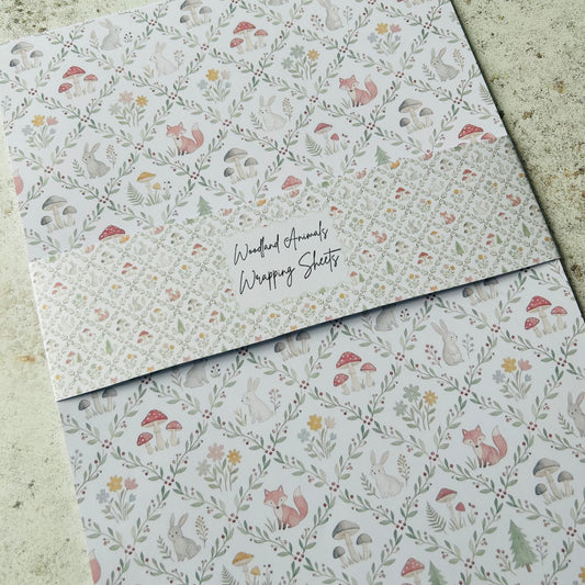 Woodland-themed wrapping paper with foxes, mushrooms, and flowers on a textured surface.