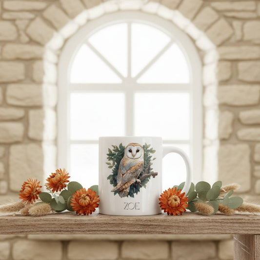 Mug with owl design on a wooden surface with flowers and a stone wall background