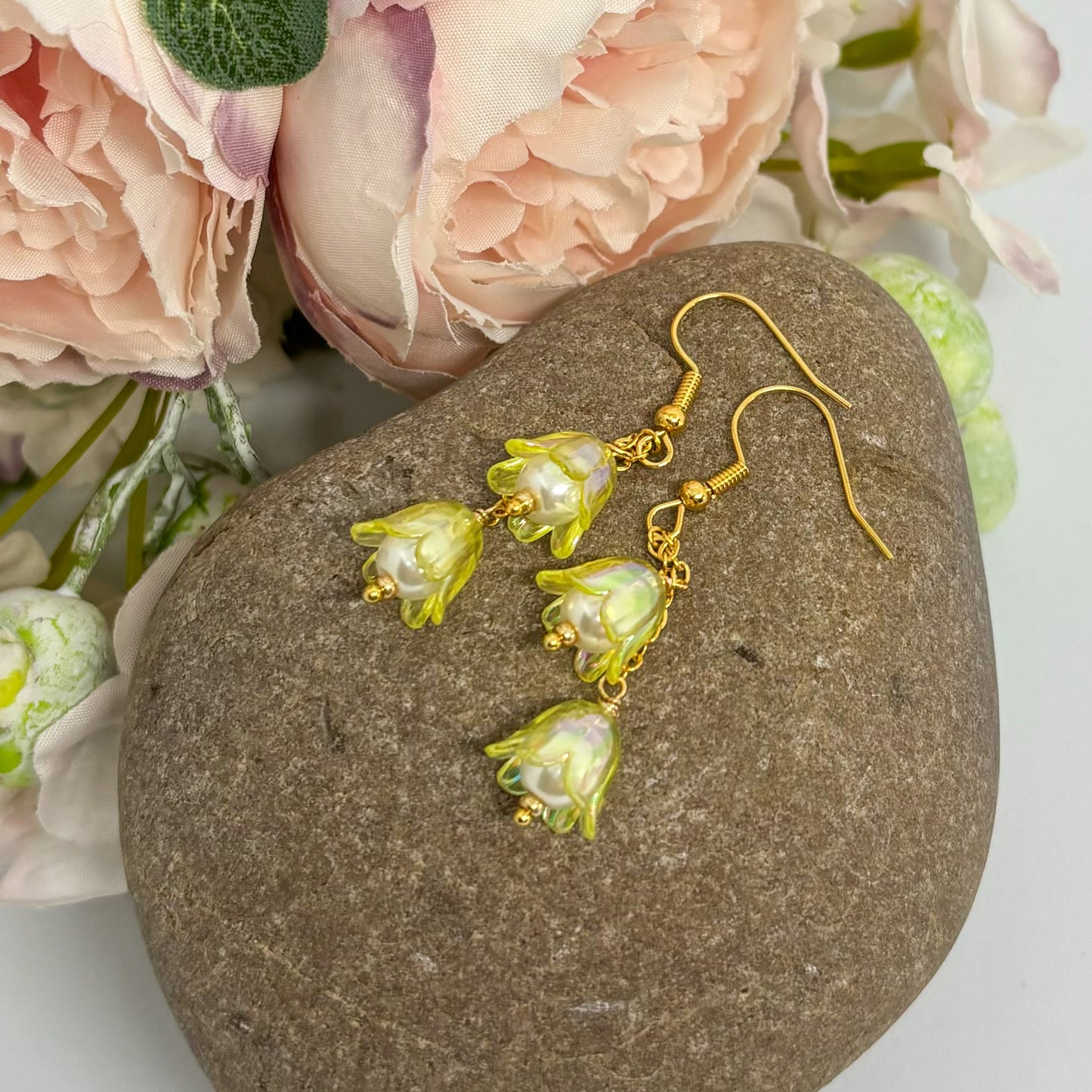 yellow floral earrings with gold hooks on a stone,