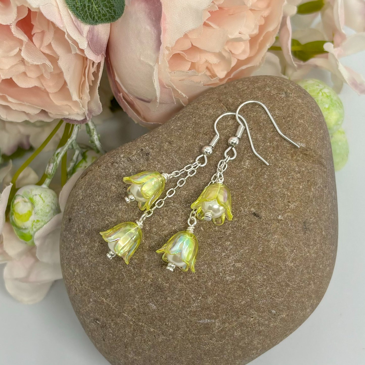 yellow floral earrings with silver hooks on a stone