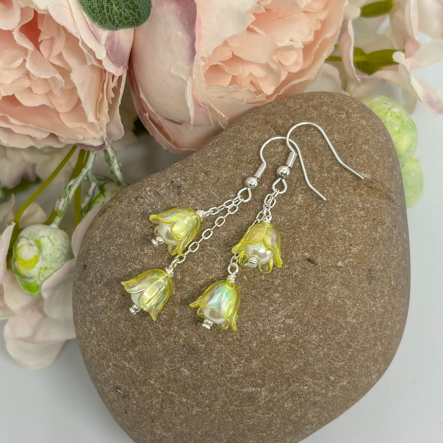 yellow floral earrings with silver hooks on a stone