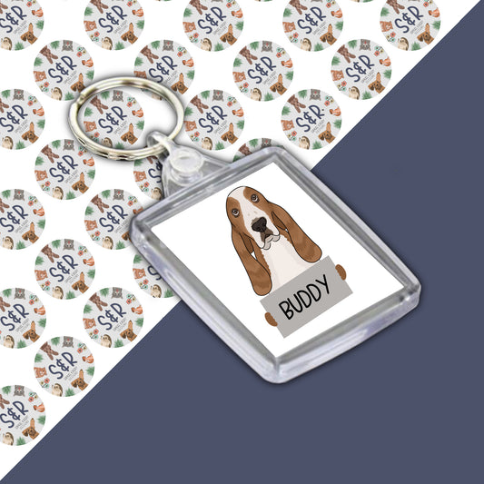 A double-sided personalised acrylic keyring featuring an illustration of a basset hound dog on a white background with the name 'Buddy' printed on the front.