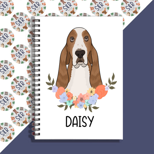 A notebook with a spiral binding featuring a graphic of a basset hound dog on the front cover, with a floral design in the background.