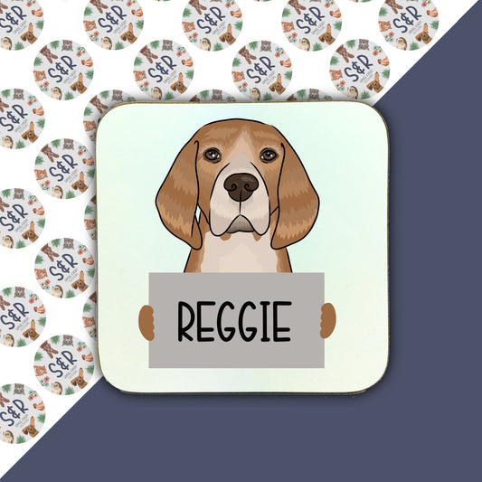 A square coaster with a personalised illustration of a beagle dog with the name 'Reggie' printed on it.