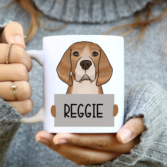 A person holding a white coffee mug with a colourful illustration of a beagle dog on it.