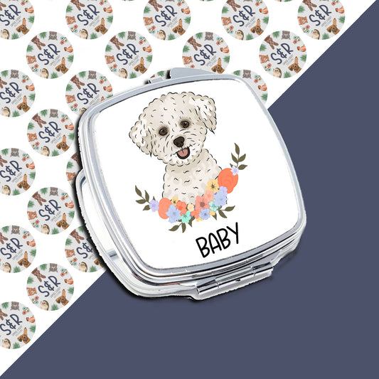 A personalised compact mirror with an illustration of a Bichon Frise dog surrounded by colorful flowers on the front, with the text 'Baby' below the image.