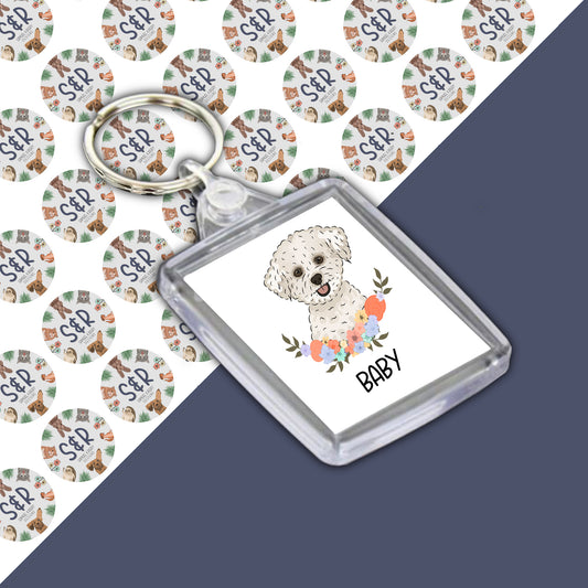 A personalised double-sided Bichon Frise keyring with an illustration of a dog in a floral design, housed in a clear acrylic casing.