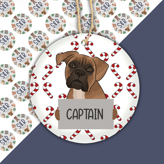 A ceramic Christmas ornament featuring an illustration of a boxer dog in the center, surrounded by Christmas-themed decoration patterns.