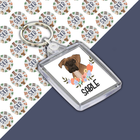 A personalised keyring featuring an illustration of a boxer dog with a floral design on a green background, placed on a keyring with the brand name 'Samuel & Rigby'.