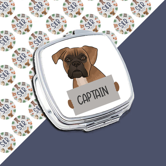 A personalised compact mirror with an image of a boxer dog and the name 'Captain' written on it, alongside a pattern of round green and white designs.