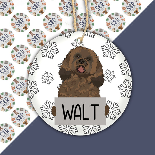 A ceramic Christmas decoration featuring a cavapoo dog with the name 'Walt' on a tag, surrounded by snowflakes.