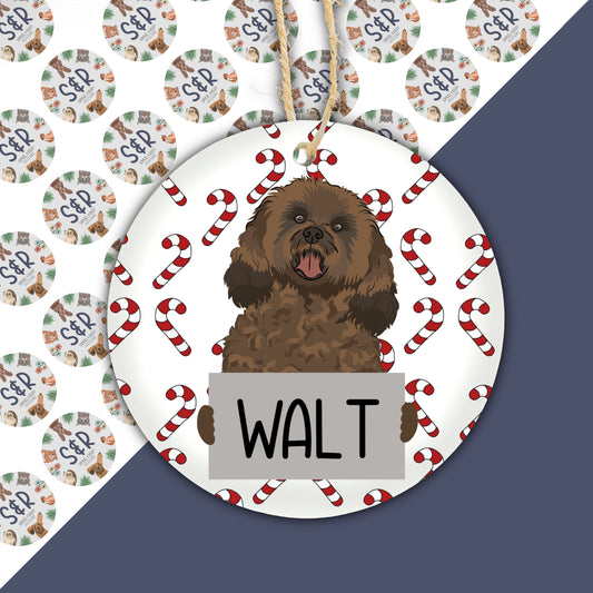 A ceramic Christmas ornament featuring a cavapoo dog illustration with the name 'Walt' on the tag, surrounded by holiday-themed decorations.