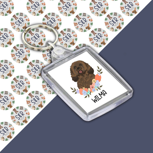 A personalised acrylic keyring featuring an illustration of a cavapoo dog with a floral design and the name 'Willa' on the keyring.