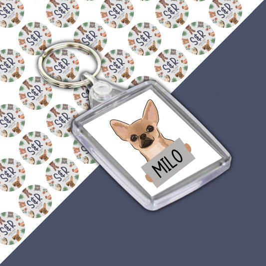A personalised acrylic keyring featuring a cartoon chihuahua dog with the name 'Milo' printed on it.