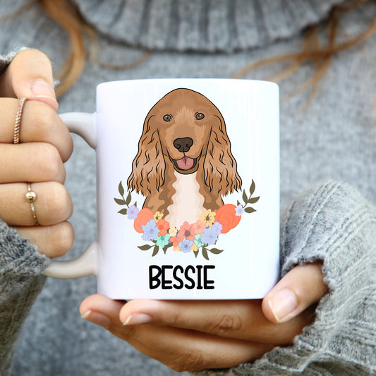 A white ceramic mug with a colourful floral design and a cartoon illustration of a Cocker Spaniel dog in the center.