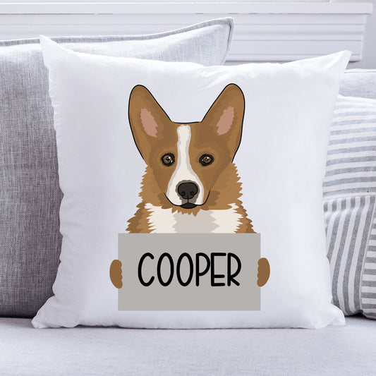 A square-shaped, white personalised pet cushion with a printed corgi dog design at the centre, holding a sign with the text 'Cooper'.