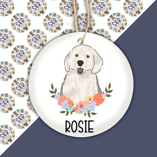 A ceramic Christmas decoration featuring an illustration of an English Sheepdog surrounded by a floral wreath, with the name 'ROSIE' personalized on the bauble.