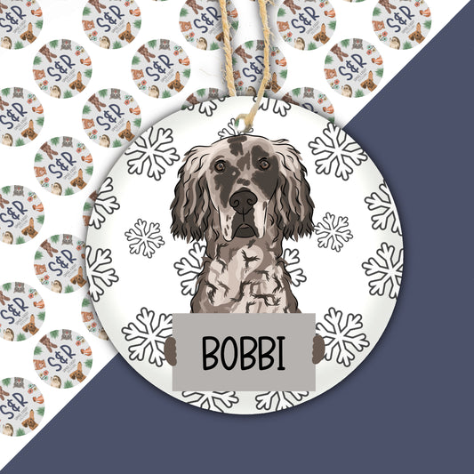 A ceramic Christmas ornament featuring an illustration of an English Setter dog with snowflakes around it, personalised with the name 'Bobbi'.