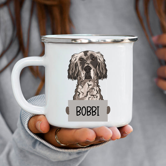 A white enamel mug with a personalised engraving of an English Setter dog breed, held in a person's hand.