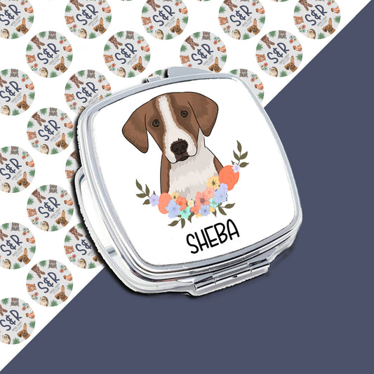 A personalised compact mirror with a sublimated design of a foxhound dog with flowers around the design, with the name 'Sheba' printed on the front.