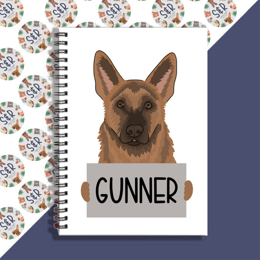 A notebook with a drawing of a German Shepherd on the cover, with the name 'Gunner' written on the front.