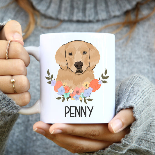 A person holding a white coffee mug with a colourful floral design and a Golden Retriever dog illustration on the side with the name 'Penny'.