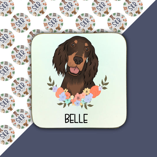 A square coaster with an illustration of a brown dog, likely a Gordon Setter, surrounded by a floral pattern. The coaster has a glossy finish and is labeled with the name 'Belle'.