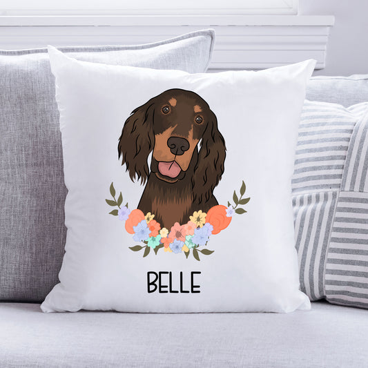 A square-shaped cushion with an illustration of a brown and white dog, likely a Gordon Setter, surrounded by a floral pattern. The cushion has the name 'Belle' printed on it.