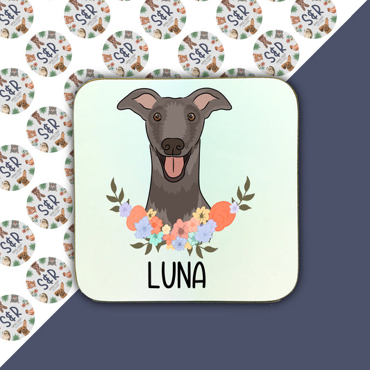 A square coaster with a illustration of a greyhound dog surrounded by a floral wreath, with the name 'LUNA' at the bottom.