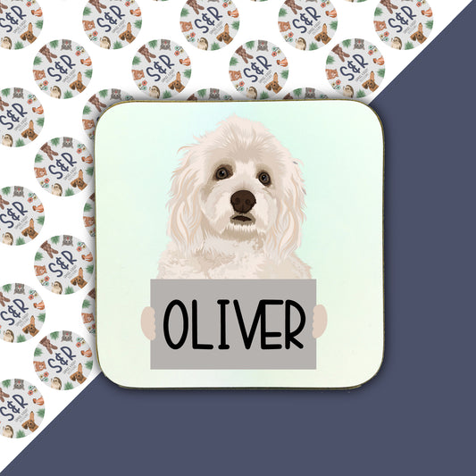 A personalised square coaster with an image of a Havanese dog and the name 'Oliver' printed on it, against a patterned background.