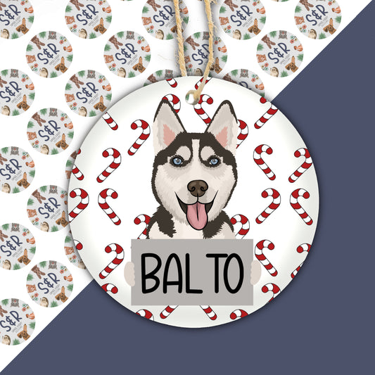 A ceramic Christmas ornament featuring a cartoon illustration of a Husky dog with a red and white color scheme, surrounded by Christmas-themed decorations.