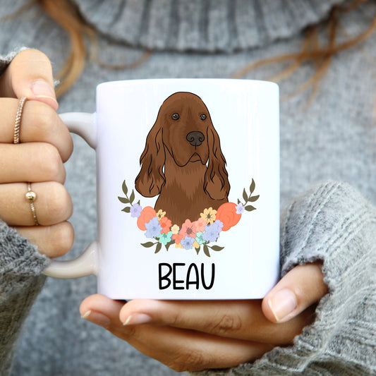 A white coffee mug with a colorful illustration of an Irish Setter dog surrounded by a floral pattern, with the word 'BEAU' underneath the image.
