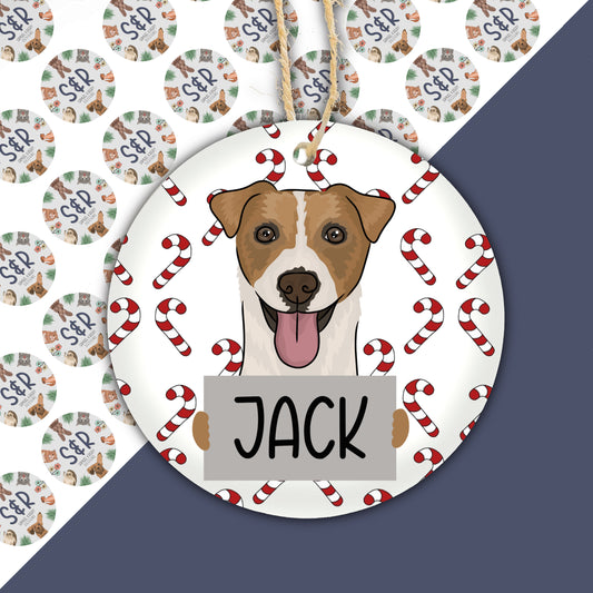 A ceramic Christmas ornament featuring a cartoon illustration of a Jack Russell dog with a red and white color scheme and the name 'Jack' on the ornament.