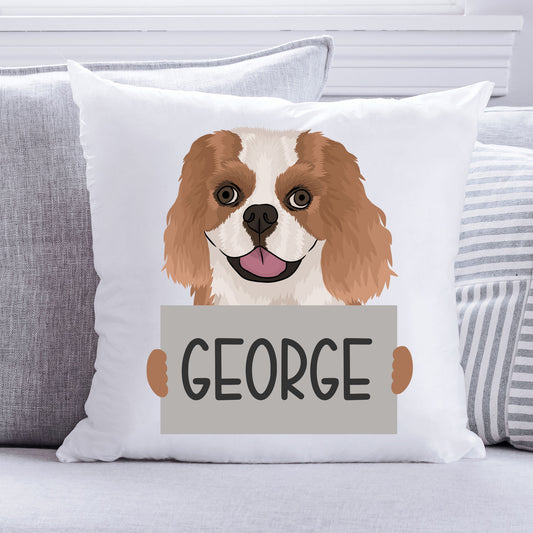 A personalised cushion featuring an illustration of a King Charles Spaniel dog with the name 'George' printed on it, sitting on a grey background.