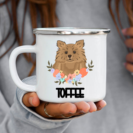 A white enamel mug with a colorful floral design and a cartoon depiction of a Pomeranian dog at the center.