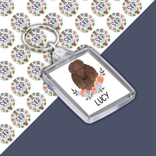 A double-sided personalised dog keyring featuring an illustration of a poodle dog with a floral design in a clear acrylic casing.