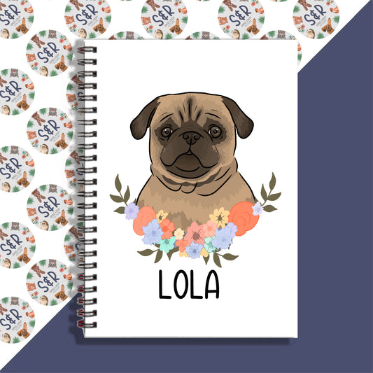 A personalised notebook with a drawing of a pug dog surrounded by a floral pattern on the cover.