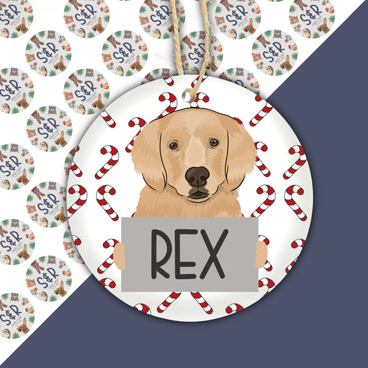 A ceramic Christmas ornament featuring an illustration of a golden retriever dog with the name 'Rex' written on it, surrounded by Christmas-themed decorations.