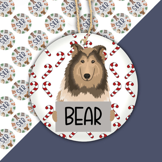 A ceramic Christmas ornament featuring a cartoon illustration of a Rough Collie dog with the text 'BEAR' on the lower part, surrounded by Christmas-themed elements.